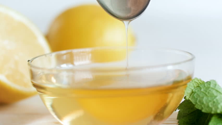 Closeup slow motion video of honey slowly dripping from spoon in glass jar on white wooden table - Powered by Shutterstock - Get 15% off with code: PIKWIZARD15