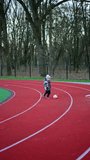 Lovely kid runs by the stadium following the ball. Happy active toddler boy playing football outdoors in autumn. Vertical video.
