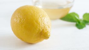Closeup 4k video of female hand cutting ripe yellow lemon with shart knife on white wooden table