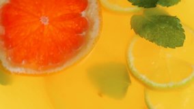 Closeup slow motion video of rotating fruits and mint in lemonade jar