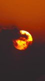 great sun rising between clouds, shot with telephoto lens. Vertical video