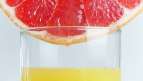 Closeup 4k video of juice droplets flowing in glass from grapefruit or red sicilian orange