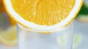 Macro slow motion video of fresh juice flowing from orange slice in glass