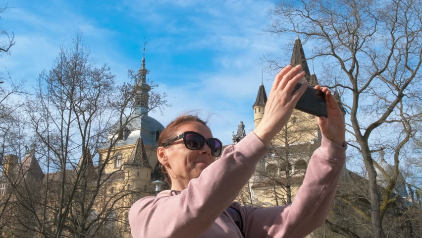 Photo by castle in hungary. A nice woman with happy emotiona takes photo against historical castle in Hungary.
