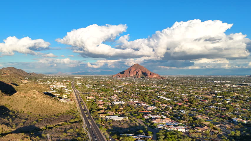 Aerial footage of Phoenix, Arizona with Camelback Mountain glowing red in the evening sun on a cloudy day