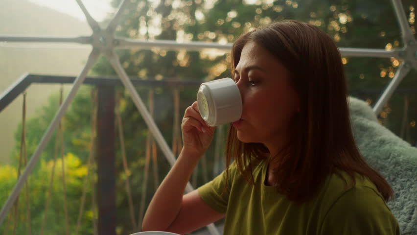 Worried woman distracts from work for break to take sip of fresh tasty coffee. Woman continues to hold cup in right hand gazing thoughtfully into middle Royalty-Free Stock Footage #3472786703