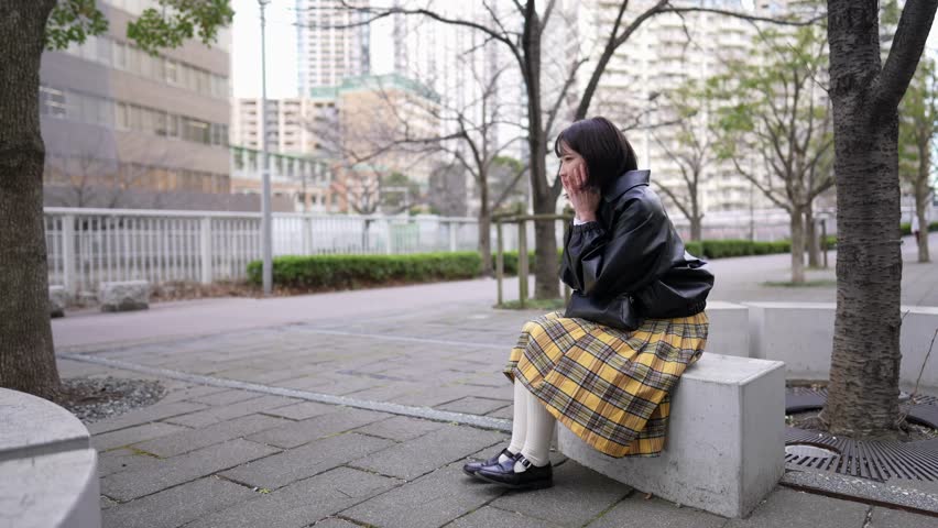 A Japanese woman in her 20s sitting in a park around Gotanda Station, Shinagawa-ku, Tokyo in winter 