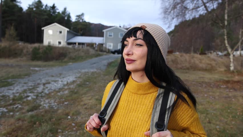 A thoughtful woman in a chic mustard sweater and beanie takes in the calm of the rural surroundings. Pensive Woman in Mustard Sweater Enjoying Countryside Solitude