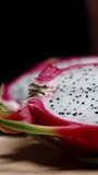 Vertical video. A young woman is eating the white flesh of the Dragon fruit with a spoon. Close-up, in slow motion.