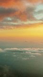 Flying in bright clouds over sea in bright sunset colors. Vertical video
