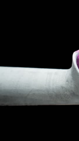 Vertical video. The ice-covered ice cream scoop and the pink ice cream ball melt, drip down, and disappear. Time-lapse on a black background.