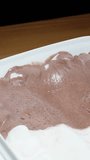 Vertical video. I shape a scoop of chocolate ice cream using a special spoon, close-up.