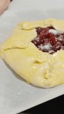 They transfer the cherry galette on a baking sheet lined with parchment paper. Vertical video.