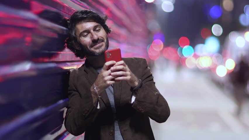 View of one young man with smartphone at night time with city view landscape and traffic lights in the background mobile phone.  Royalty-Free Stock Footage #3473062973