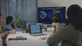 Multiracial office people group talking during staff meeting ina boardroom. African american man team leader holding a meeting and pointing to a diagrams on a big screen in the office. - Powered by Shutterstock - Get 15% off with code: PIKWIZARD15