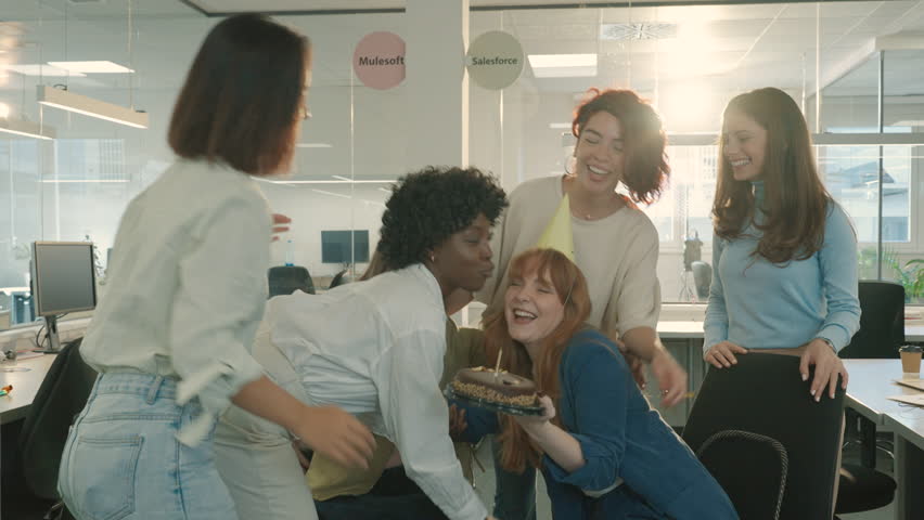 A diverse businesswomen are celebrating birthday at office with an excited birthday girl with a birthday cake. A multicultural businesspeople having a birthday celebration party at office.