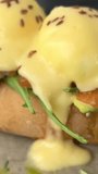 eggs Bendict on brioche buns with lightly salted salmon and cream with cheese beautiful serving in a restaurant delicious breakfast dish on a plate with herbs sprinkled with flax seed. summer morning