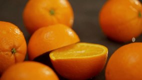 A whole orange falls on the table and spectacularly splits in half. Many citrus fruits are laid out on a dark surface. High quality FullHD footage - Powered by Shutterstock - Get 15% off with code: PIKWIZARD15