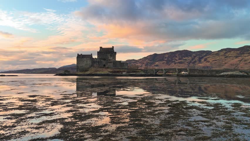 Drone view of Eilean Donan Castle during low-level flight over water