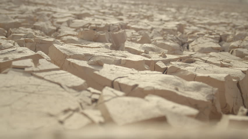 MACRO, DEPTH OF FIELD: Dry mud cracks shining in heat create an interesting landscape. Rugged rocky terrain providing no refuge for plants or animals. Global warming drying out once fertile land. Royalty-Free Stock Footage #34731910