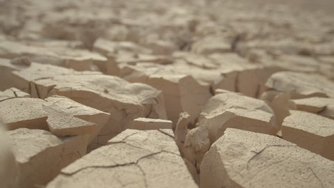MACRO, DEPTH OF FIELD: Dry mud cracks shining in heat create an interesting landscape. Rugged rocky terrain providing no refuge for plants or animals. Global warming drying out once fertile land. Video Stok