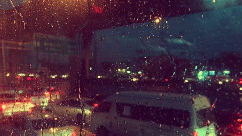 4K video of blurry traffic jam in street city on the road with heavy rain on mirror from inside of car bus on before morning with busy and bored start working day on vintage color tone style