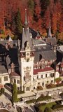 Aerial around view of Peles Castle in autumn forest, Sinaia, Romania. Summer residence of the kings of Romania. Vertical video