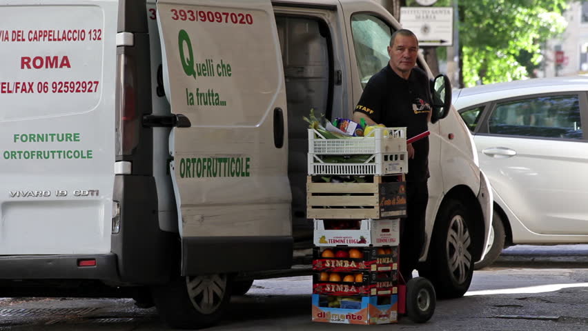 ROME - CIRCA MAY 2012 A delivery man stands next to his delivery van and a stack