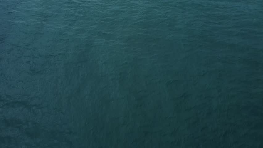 Advancing Aerial Drone Push Shot Looking Down on White Island Lighthouse Protruding into the Atlantic Ocean while Waves Crash on the Rocks.