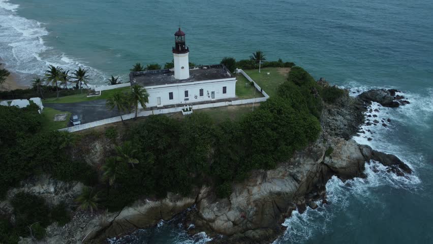 Static Aerial Drone Shot Looking Down on White Island Lighthouse Protruding into the Atlantic Ocean while Waves Crash on the Rocks.