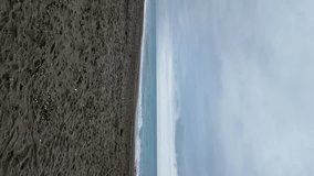 Serene beach by the sea on a cloudy day - vertical video