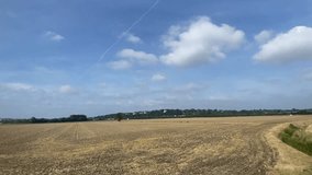 Wide shot countryside and farmland clouds and blue sky out of a window of train, tracking along flat British UK southern England  - stock footage video