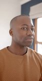 Vertical video of portrait of happy african american man smiling at home, slow motion. Lifestyle and domestic life, unaltered.