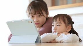 asian daughter and mother using tablet together in living room 
