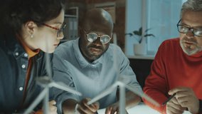 Team of diverse engineers sitting in dark office and discussing renewable energy project when having business meeting in the evening - Powered by Shutterstock - Get 15% off with code: PIKWIZARD15