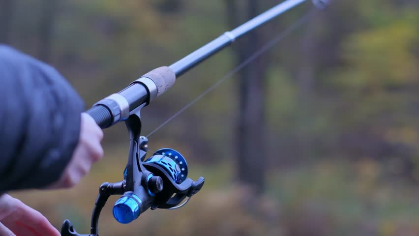 Close-up of a reel of a fishing rod being spun by a human hand  Royalty-Free Stock Footage #3473625769