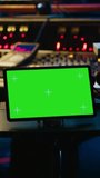 Vertical Video African american tracking engineer works with greenscreen, operates audio console with moving faders and colored meters. Specialist pressing buttons and faders to edit audio recordings