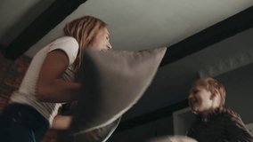 Young blonde mom having fun with her kid. Happy european mom and teenage son pillow fighting and jumping on bed during self-isolation and quarantine. Concept of childhood, motherhood and family. - Powered by Shutterstock - Get 15% off with code: PIKWIZARD15