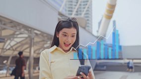 Attractive Asian businesswoman celebrate after stock market grow up. Beautiful female trader look at hologram visual technology after win trading in stock market on smartphone on the busy city street. - Powered by Shutterstock - Get 15% off with code: PIKWIZARD15