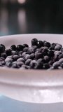 mixing fresh and frozen blueberries in a white plate with wooden spoons preparing a dessert to restore vision taking care of the eyes healthy nutrition. frozen berries for the winter