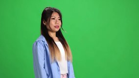 Confident young Asian lady, student in casual outfit looking at camera against vibrant green studio background. Copy space. Concept of human emotions, self-expression, fashion, style. Ad