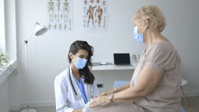 4K video footage of a Smiling young Caucasian female doctor hold old woman patient hand support and comfort in hospital. Caring nurse caress happy optimistic mature client at consultation. Healthcare 
