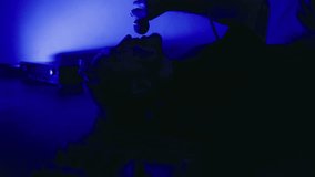 Vocal performance: Rapper or singer male reclines, expressing emotions under electric blue light while recording vocals in studio