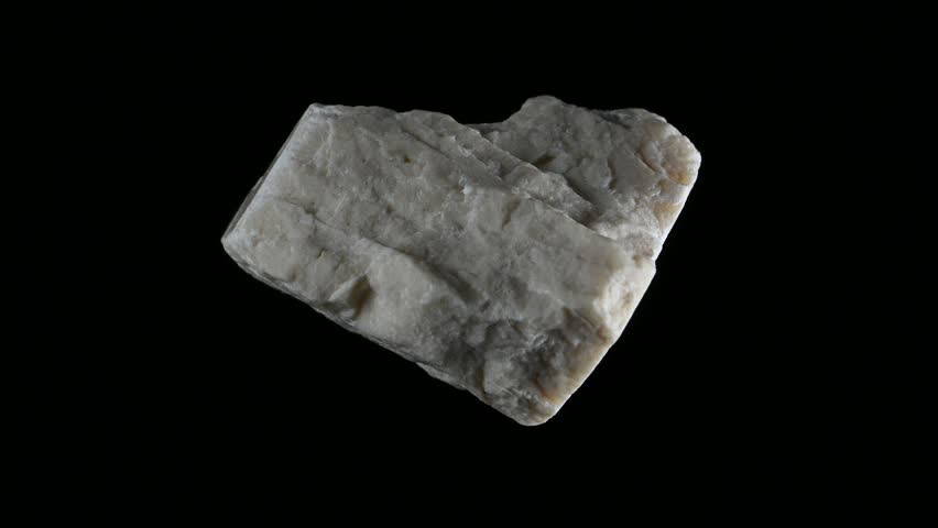 White Aragonite (Calcium carbonate) sample rotating slowly against a black background.