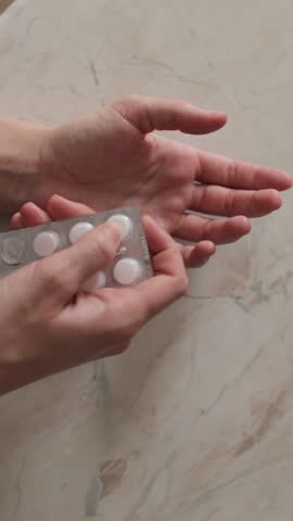Pills Out Of Blister Pack in a woman's hand, close up. Vertical video.