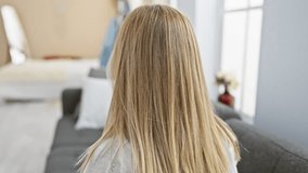 A blonde woman listens to music on headphones at home, with a cozy living room setting in the background. - Powered by Shutterstock - Get 15% off with code: PIKWIZARD15
