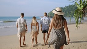 Cheerful caucasian female in sun hat walks by sea on sandy tropical beach with friends group turns, asks to join. Pretty young traveler woman on luxury resort shore smiles cheerfully, invites follow. - Powered by Shutterstock - Get 15% off with code: PIKWIZARD15