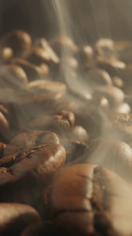 Roasting coffee beans with smoke on dark background. Smoke comes from fresh coffee seeds. Slider Macro vertical shot