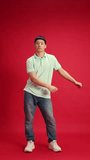 Happy, joyful man, student in denim jeans and T-shirt dancing in motion against red studio background. Success. Concept of human emotions, fashion and beauty, self-expression, work and hobby.