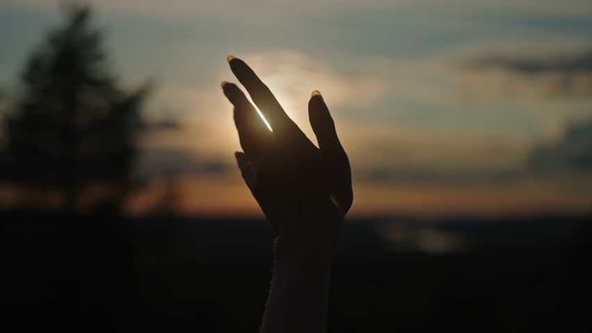 Silhouette of a female hand reaching out to the sun. Religion and prayer, helping hand. Happy girl extending her hand. Silhouette of a hand at sunset. Forest of northern Finnish Lapland  Royalty-Free Stock Footage #3474046091